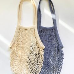 two purses sitting next to each other on a white surface, one is blue and the other is beige