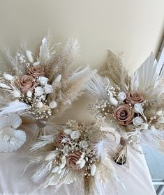 two wedding bouquets made out of feathers and flowers on top of a white table