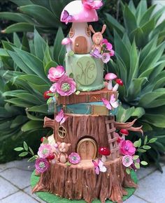 a cake made to look like a tree stump with pink flowers and mushrooms on top