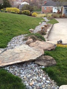 a stone path in the middle of a yard with grass and rocks on both sides