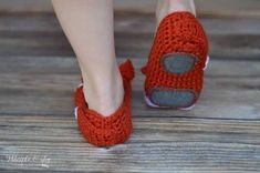 a woman's feet wearing red slippers on top of a wooden floor