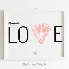 a framed print with the word made with love written on it and a pink handprint in the shape of a baby's foot