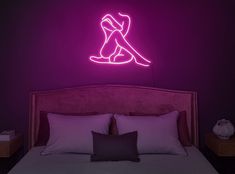 a neon sign above a bed in a room with purple walls and white linens