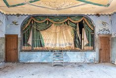 an empty stage with green curtains and steps leading up to the curtained area that is painted blue