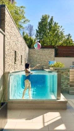 a woman is playing with a ball in the pool