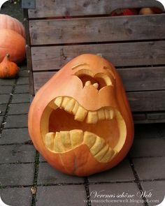 two carved pumpkins sitting next to each other on a brick walkway with wooden crates in the background