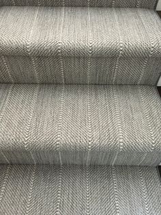 a carpeted staircase with grey and white rugs