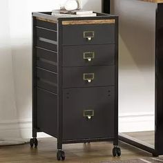 a black and gold filing cabinet with drawers on wheels in front of a white wall