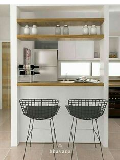 two black chairs sitting next to each other in front of a white counter top and shelves