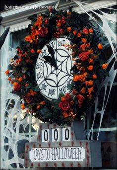 a clock decorated with orange flowers in front of a store window that says days to halloween