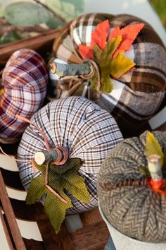 several decorative pumpkins are sitting on a wooden crate with fall leaves and plaid fabric