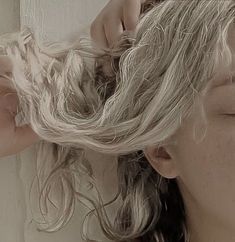 a woman is blow drying her hair in front of a mirror with another person's hand