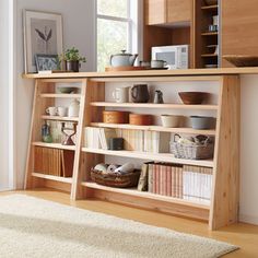 a book shelf with many books and bowls on it in front of a large window