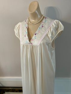 "Very sweet retro night gown from Movie Star in excellent condition. Size is M. My dress form is a Small and I think a lady who wears either a S or M in a dress can wear this night gown. Color is a creamy beige and silky nylon fabric has a pretty drape and flow. Adorable detail at the neckline and shoulders. On either side of the V neckline and just below the bottom of the V is a bit of softly quilted fabric with tiny embroidered flowers. The inside edge of the V is scalloped and along the outsi Feminine Cream Sleepwear For Bedtime, Feminine Cream Nightgown With Lace Trim, Feminine Beige Nightgown For Loungewear, Beige V-neck Nightgown For Sleep, Beige Lace Trim Nightgown For Bedtime, Cream V-neck Sleep Dress, Beige Nightgown For Wedding Night, Spring Wedding Night Beige Nightgown, Embroidered Nightgown For Spring