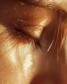 the eye of a woman with long eyelashes and gold eyeshadow, close up