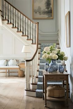 there is a blue and white vase with flowers on the table next to the stairs