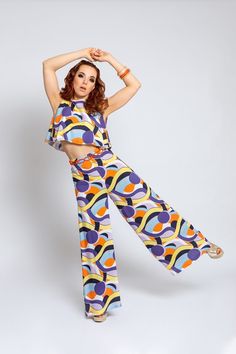 Groovy baby! We're bringing the 1960s back to life! Great designers like Emilio Pucci shaped this decade with their psychedelic patterns. Our high-waisted trousers are a homage to this designer with his unusual and colorful prints. Our trousers have wide flared legs and are made from a light, flowing viscose that is ideal for warm temperatures. The trousers close at the back with a hidden zip. Dimensions: Side length 115 cm Inseam length 83 cm Hem width (1/2) 41.5 cm Material: 100% viscose Machi Retro Multicolor Party Bottoms, Fitted Retro Print Groovy Bottoms, Fitted Bottoms With Retro Print In Groovy Style, Retro High-waisted Multicolor Pants, Retro Multicolor High-waisted Pants, Fitted Retro Pants With Retro Print, Retro Print Wide Leg Bottoms, Retro Wide Leg Bottoms With Retro Print, Super B