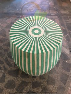 a green and white striped ottoman sitting on top of a tiled floor next to a wall