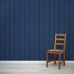 a wooden chair sitting in front of a blue wall with vertical stripes on it's side