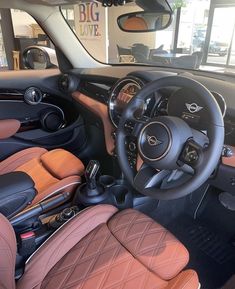 the interior of a car with brown leather seats and steering wheel, in a showroom