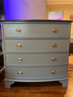 a blue chest of drawers with brass pulls on it's sides in a living room