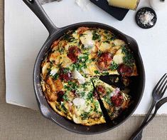 a pizza in a pan on top of a table next to utensils and cheese