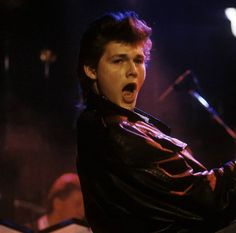 a young man singing into a microphone on stage