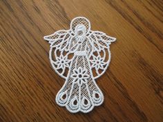 an embroidered angel ornament sitting on top of a wooden table