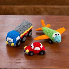 three crocheted toy cars and an airplane on a table