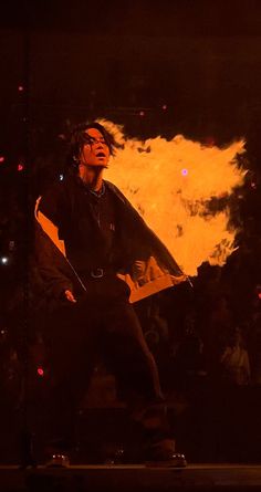 a man standing on top of a skateboard in front of a fire filled background