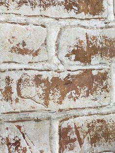 an old brick wall with white and brown paint