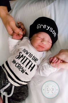 a newborn baby wearing a black and white hat is being held by someone's hand