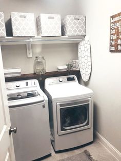 a washer and dryer in a small room with shelves on the wall above them