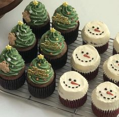 cupcakes decorated with frosting and christmas trees on a cooling rack, ready to be eaten