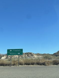 a street sign on the side of an empty road with mountains in the back ground