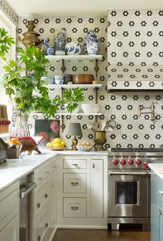 a kitchen with white cabinets and black and white wallpaper on the backsplash