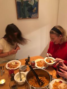 two women sitting at a table with plates of food and utensils in front of them