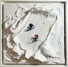 two people skiing down a snow covered slope in front of a white frame with paint on it