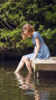 a woman is sitting on a dock in the water