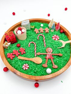 a wooden bowl filled with green grass covered in candy canes and gingerbreads