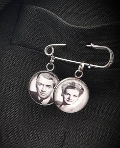 pair of earrings with photo of elvis presley hanging from hooks on black fabric backgroung