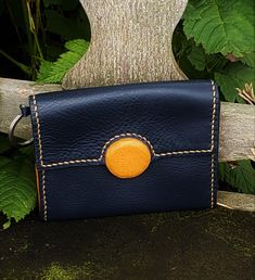 Nice wallet to slip into the pocket. Made of dark blue colored leather with tan leather accent. Interior lined with goat leather. Four card slots (can hold more) Ample space for your papers. Zippered pocket on the back. Flap closure with magnetic button Ring for keys. Hand sewn Dimensions: 14 (W) x 11.5 (H) cm 5 1/2 (W) x 4 1/2 (H) " Delivered in a linen and cotton pouch Other colors and arrangements available on request. Artisan Hand-stitched Wallets For Everyday Use, Artisan Hand-stitched Wallets, Handmade Blue Leather Wallet, Leather Hand-stitched Coin Purse For Everyday Use, Handmade Blue Wallet For Everyday Use, Blue Leather Trifold Wallet For Everyday Use, Hand-stitched Leather Coin Purse For Daily Use, Blue Handmade Wallet, Blue Leather Coin Purse For Daily Use