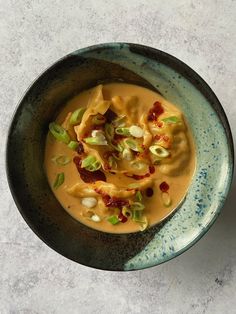 a bowl filled with soup on top of a white countertop next to a spoon