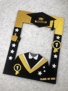 a graduation photo frame made out of paper with stars and ribbons on the front, in black and gold