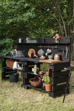 an old fashioned stove with pots and pans on it's shelf in the grass