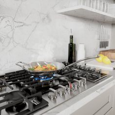 a frying pan on top of a gas stove in a kitchen with marble counter tops