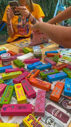 a group of people sitting around a table covered in candy boxes and playing with a cell phone