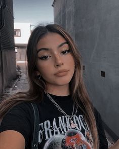 a woman with long brown hair wearing a black shirt and holding a cell phone in her hand