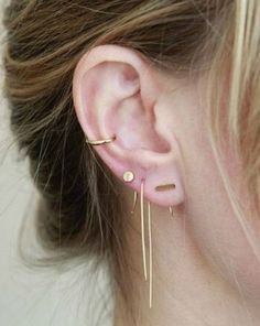 a woman wearing ear piercings in gold