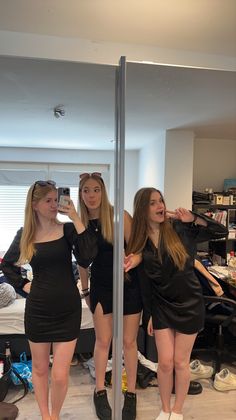 three young women standing in front of a mirror